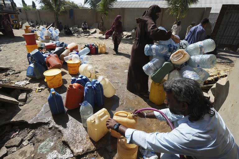 Las personas obtienen agua potable de un punto de recolección de agua en un barrio marginal, en Karachi, Pakistán