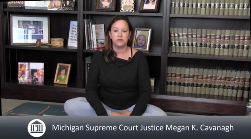 Michigan Supreme Court Justice Megan Cavanagh sits cross-legged in a yoga pose on a yoga mat speaking about well-being in the legal profession. She announced the release of a task force report on well-being in the law. She spoke about yoga, being mindful and deemphasizing alcohol at social events. From a video released August 22, 2023, by the Supreme Court on YouTube.