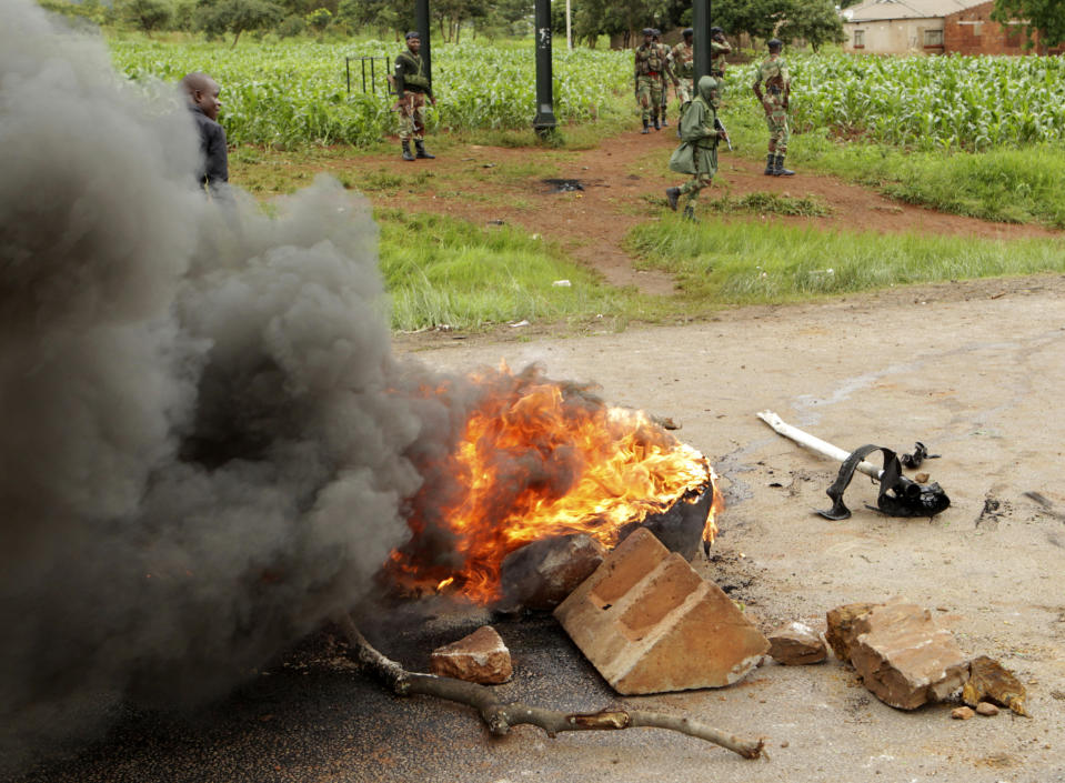 Soldiers patrol near a barricade A soldier patrols as protestors gather during a demonstration over the hike in fuel prices in Harare, Zimbabwe, Tuesday, Jan. 15, 2019. A Zimbabwean military helicopter on Tuesday fired tear gas at demonstrators blocking a road and burning tires in the capital on a second day of deadly protests after the government more than doubled the price of fuel in the economically shattered country. (AP Photo/Tsvangirayi Mukwazhi)