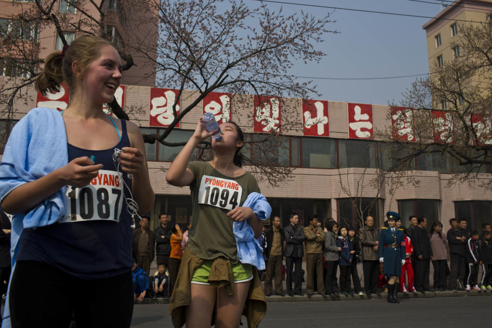 Tourists who competed in the shorter distance segments of the Mangyongdae Prize International Marathon in Pyongyang, North Korea rest at the end of the race on Sunday, April 13, 2014. From left are Harriet Harrper-Jones, England, and Allie Wu, Taiwan. The sign behind them reads "Long Live the Shining Revolutionary Tradition of Our Party." The annual race, which includes a full marathon, a half marathon, and a 10-kilometer run, was open to foreign tourists for the first time this year. (AP Photo/David Guttenfelder)