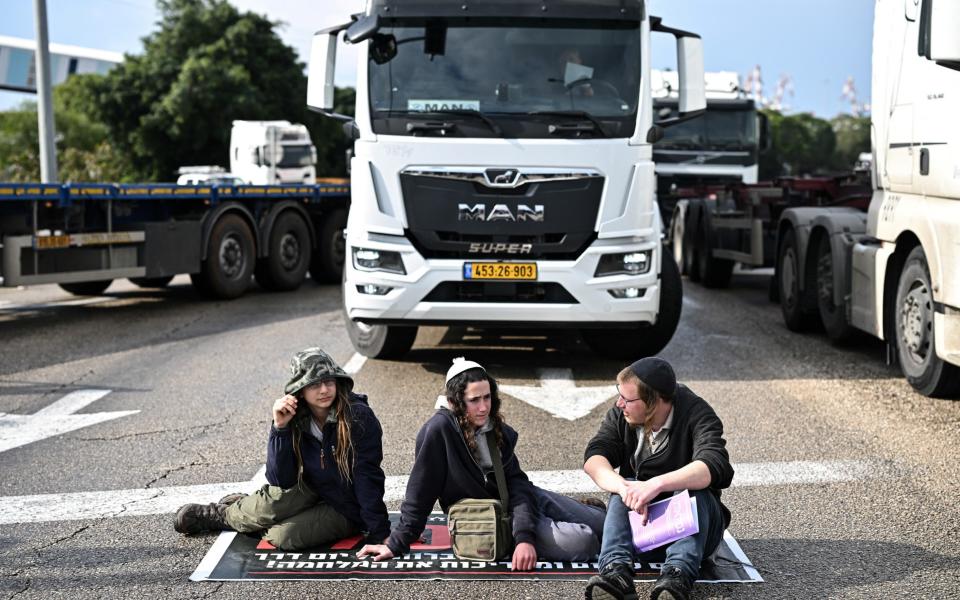 Protesters sit on the road as they aim to block the transportation of humanitarian aid