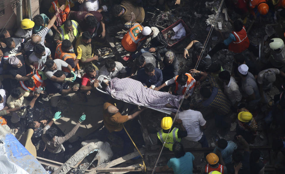 Rescuers carry the body of a victim at the site of a building that collapsed in Mumbai, India, Tuesday, July 16, 2019. A four-story residential building collapsed Tuesday in a crowded neighborhood in Mumbai, India's financial and entertainment capital, and several people were feared trapped in the rubble, an official said. (AP Photo/Rajanish Kakade)
