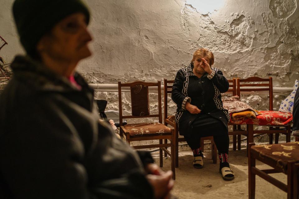 A woman in a chair, right, weeps as she and another resident take shelter in a basement in Nagorno-Karabakh.