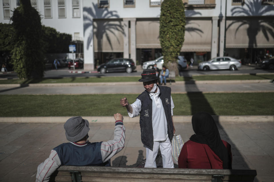 Belhussein Abdelsalam, 58, a Charlie Chaplin impersonator gives to a friend, on an avenue in Rabat, Morocco, Tuesday, March 23, 2021. When 58-year-old Moroccan Belhussein Abdelsalam was arrested and lost his job three decades ago, he saw Charlie Chaplin on television and in that moment decided upon a new career: impersonating the British actor and silent movie maker remembered for his Little Tramp character. (AP Photo/Mosa'ab Elshamy)