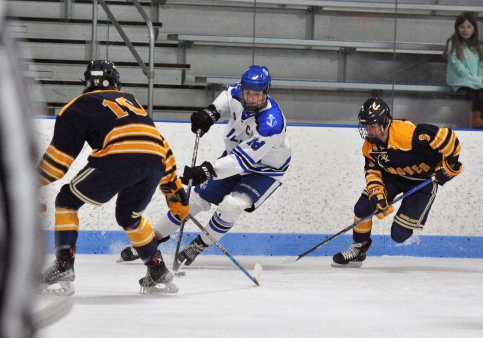 Scituate's James Sullivan, center, controls the puck as Hanover's Matt Reynolds, left, and Henry Phillips, right, move in during boys high school hockey action at the Hobomock Arena in Pembroke, Wednesday, Feb. 7, 2024.