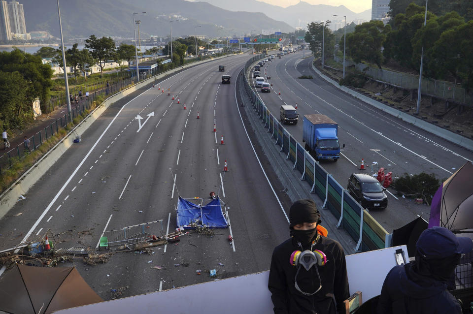 A protester stands on a barricaded bridge as traffic passes underneath near the Chinese University of Hong Kong in Hong Kong, Friday, Nov. 15, 2019. Protesters who had barricaded themselves in a Hong Kong university this week began to leave Friday after partially clearing a road they had blocked and demanding that the government commit to going ahead with local elections on Nov. 24. (AP Photo/Vincent Yu)