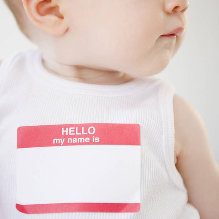 A baby with a blank hello my name is sticker on their shirt