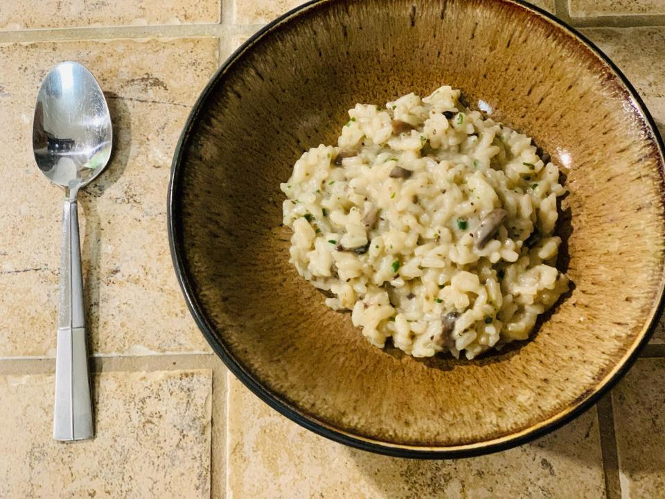 Trader Joe's mushroom risotto in a brown bowl with a spoon beside it