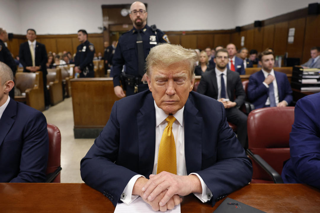 Donald Trump sits at the defense table.