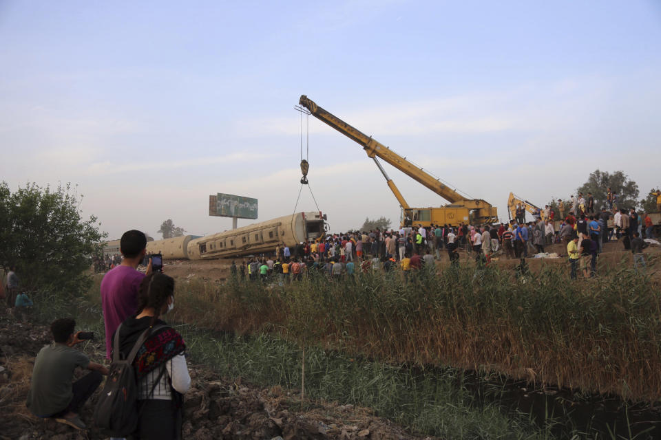 A crane is used to lift a part of a passenger train that derailed injuring some 100 people, near Banha, Qalyubia province, Egypt, Sunday, April 18, 2021. At least eight train wagons ran off the railway, the provincial governor's office said in a statement. (AP Photo/Fadel Dawood)