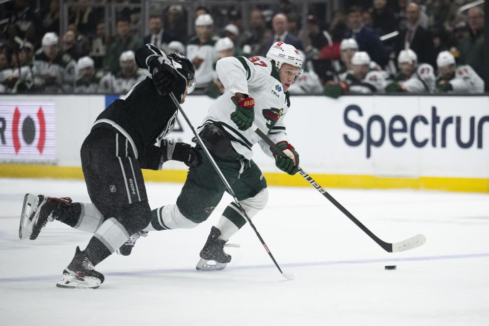 Minnesota Wild left wing Kirill Kaprizov, right, controls the puck past Los Angeles Kings defenseman Mikey Anderson, left, during the first period of an NHL hockey game, Monday, April 15, 2024, in Los Angeles. (AP Photo/Kyusung Gong)