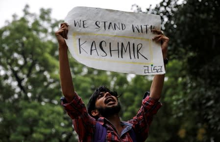 A man holds a sign and shouts slogans during a protest after the government scrapped the special status for Kashmir, in New Delhi