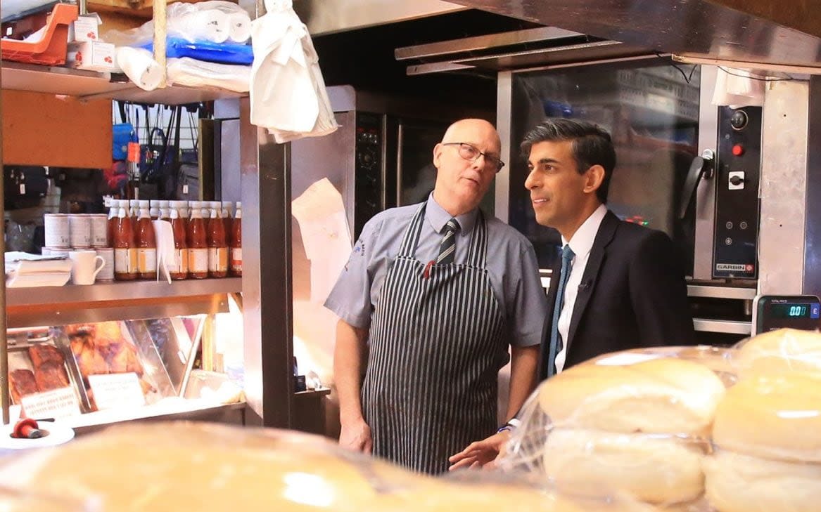 Rishi Sunak speaks to a butcher during a visit to Bury Market in Lancashire - Lindsey Parnaby/PA