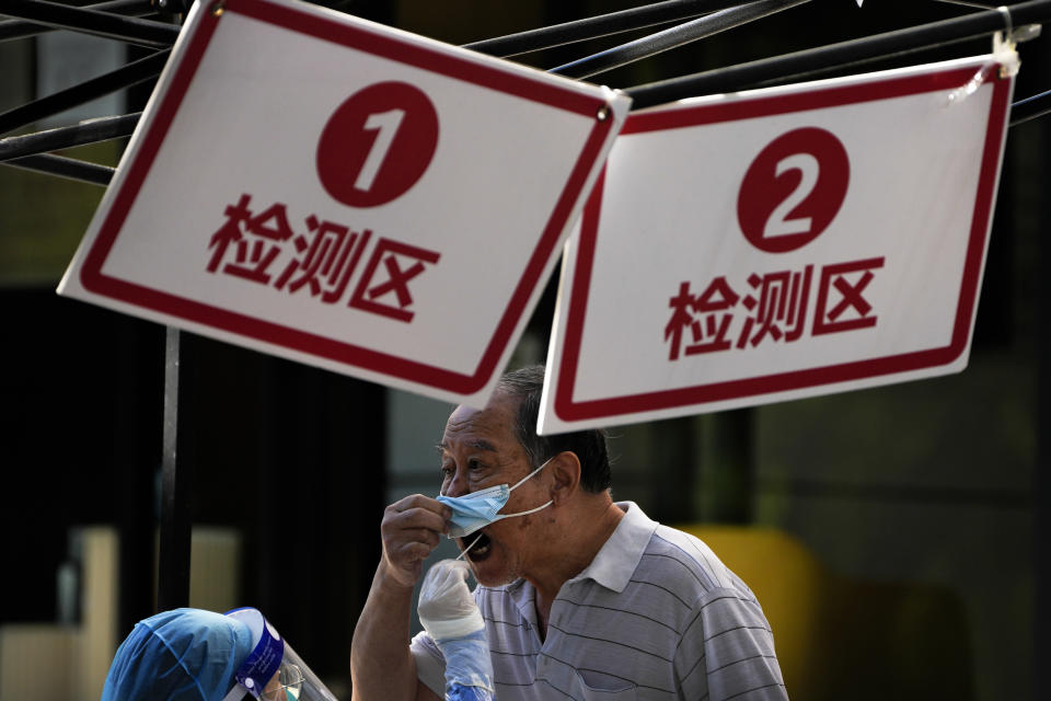 A man pulls his mask to get his routine COVID-19 throat swab at a coronavirus testing site in Beijing, Monday, Sept. 5, 2022. (AP Photo/Andy Wong)
