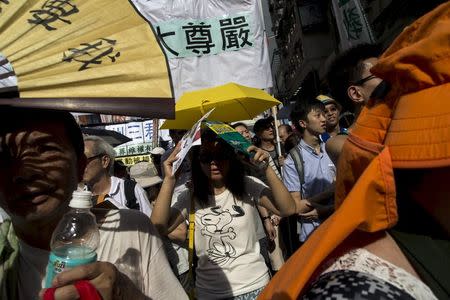 A pro-democracy protester holds a yellow umbrella, the symbol of the Occupy Central movement, during a march to demand universal suffrage in Hong Kong, China July 1, 2015. REUTERS/Tyrone Siu