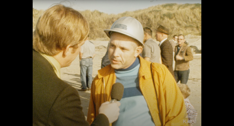 A still from television in the 1970s. A local reporter talks to a man involved in blowing up a whale carcass.