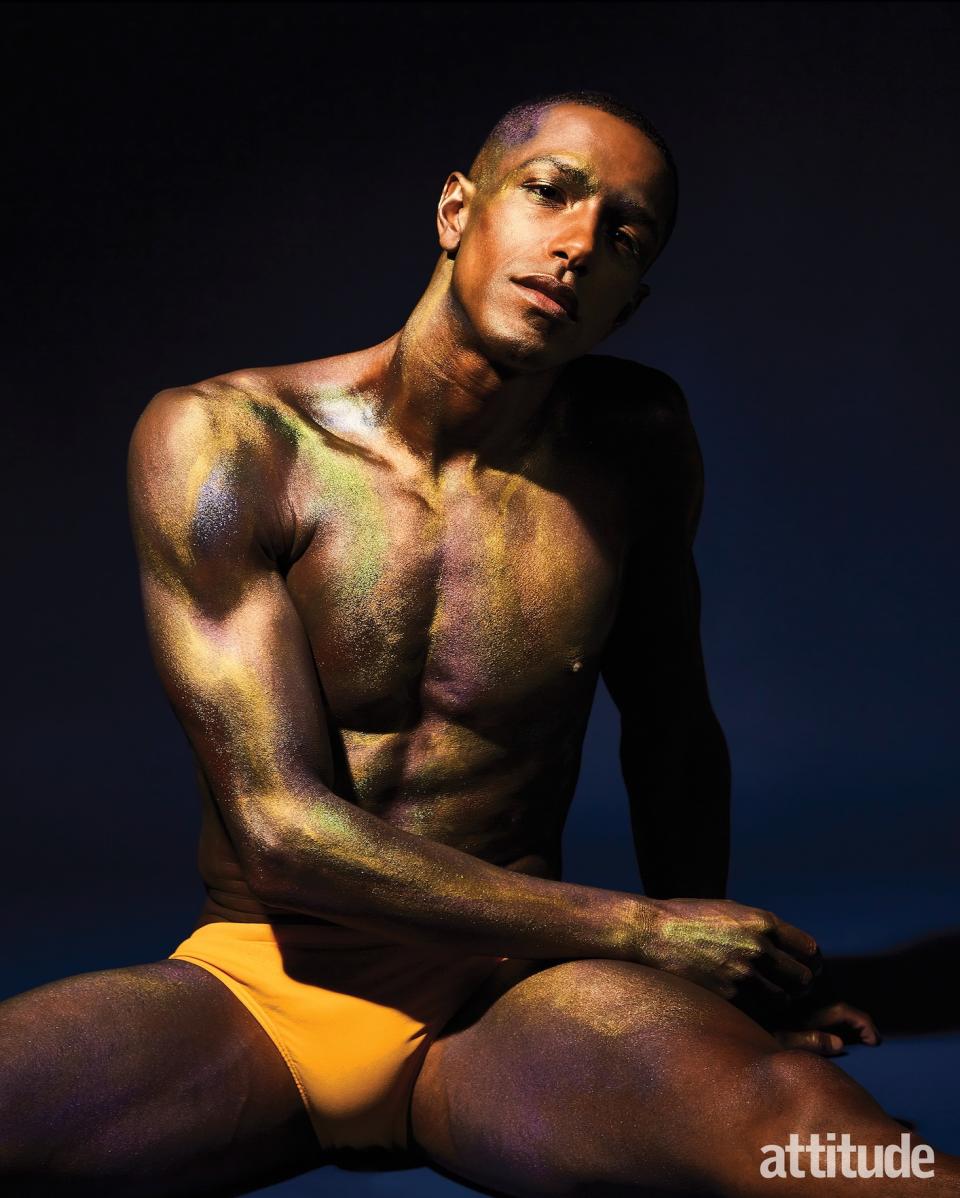 A man wearing yellow swimming trunks with golden shimmering body paint