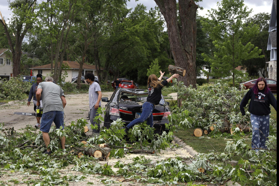 Woodridge, Ill., residents clear trees off a damaged car after a tornado passed through the area on Monday, June 21, 2021. (AP Photo/Shafkat Anowar)