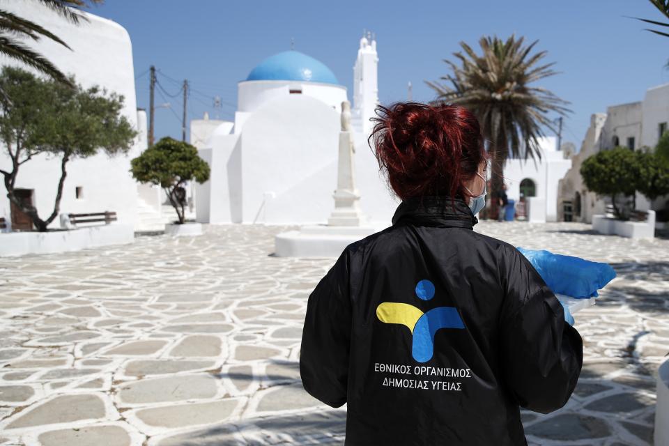 In this Monday, May 25, 2020 photo, a doctor of the National Health Organization (EODY) carries the tests for coronavirus taken on local residents on the Aegean Sea island of Sikinos, Greece. Using dinghies, a GPS, and a portable refrigerator, state doctors have launched a COVID-19 testing drive on islands in the Aegean Sea ahead of the holiday season, authorities in charge of the program said. The first round of testing was completed after trips to the islands of Milos, Kimolos, Folegandros, and Sikinos. (AP Photo/Thanassis Stavrakis)