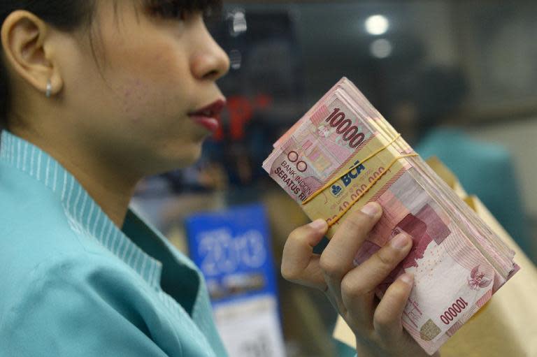 An Indonesian clerk shows a stack of rupiah notes to a customer at a money changer in Jakarta on August 28, 2013