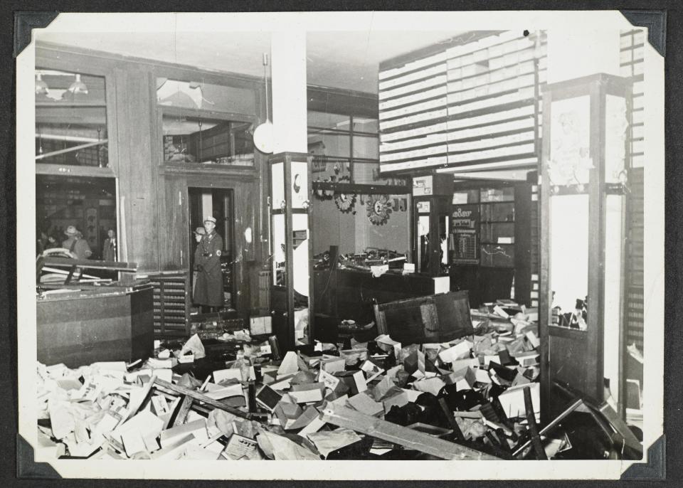 This photo released by Yad Vashem, World Holocaust Remembrance Center, shows German Nazis stand by ransacked Jewish property during Kristallnacht intake most likely in the town of Fuerth, Germany on Nov. 10, 1938. The photos were taken by Nazi photographers during the pogrom in the city of Nuremberg and the nearby town of Fuerth. They wound up in the possession of a Jewish American serviceman who served in Germany during World War II. His descendants,donated the album to Yad Vashem. (Yad Vashem via AP)