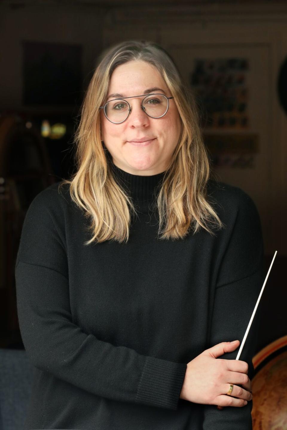 A woman holds a conductor's baton.