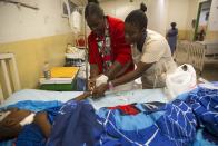 Nurses Valein Elda, left center, and Ricelin Chantale, tend to 14-year-old Miguelson Joseph at the Baptiste Mission Hospital in Kenscoff, just outside of Port-au-Prince, Haiti, Saturday, Feb. 15, 2020. Miguelson was injured when he jumped from a balcony at a branch of the Orphanage of the Church of Bible Understanding, trying to flee during a raid in which police were ordered to remove the children, after a fire swept through a nearby orphanage also run by the Pennsylvania-based nonprofit group, killing 15 children, officials said Friday. (AP Photo/Dieu Nalio Chery)