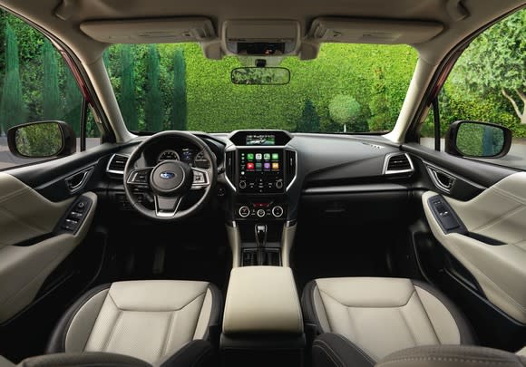 The front seats and dashboard of a 2019 Subaru Forester Touring, with two-tone leather seats and polished black and metal trims.