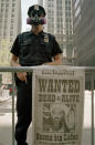 A New York City police officer stands guard at a checkpoint on the corner of Nassau and Liberty near the New York Stock Exchange in the Financial District of Manhattan, Tuesday, Sept. 18, 2001, a week after the terrorist attack on the World Trade Center. Visible on barrier is the front page of the New York Post with a photograph of Osama bin Laden and the headline reading: "Wanted Dead or Alive." (AP Photo/David Gochfeld)