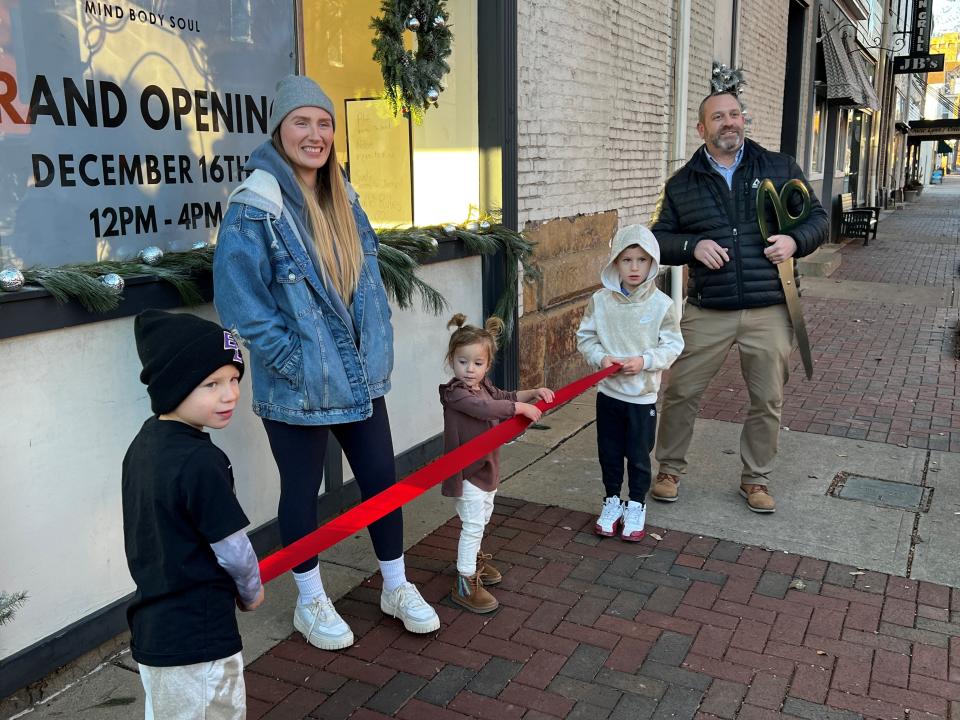 Courtney Cattran and her three children prepare to cut a ribbon to celebrate the opening Cattran's AIRE Studios at 201 W. Main St. Lancaster-Fairfield County Chamber of Commerce President Travis Markwood looks on.