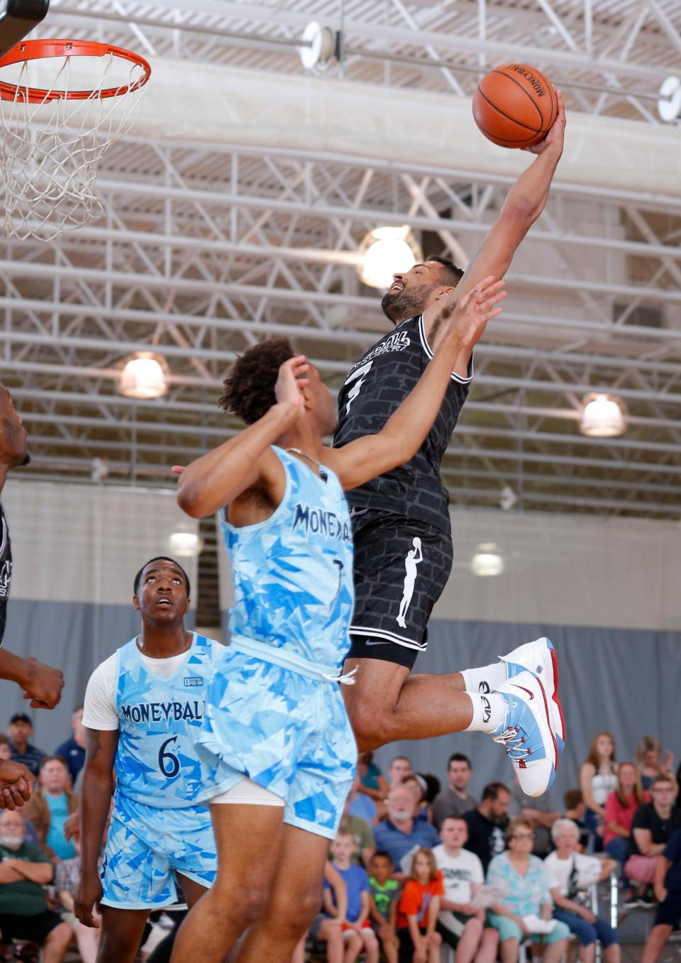 Team Roots' Devin Oliver, right, goes up for a dunk over Team Freeze's Tristan Greenidge in the Moneyball Pro-Am, Tuesday, July 2, 2019, at Aim High in Dimondale, Mich.