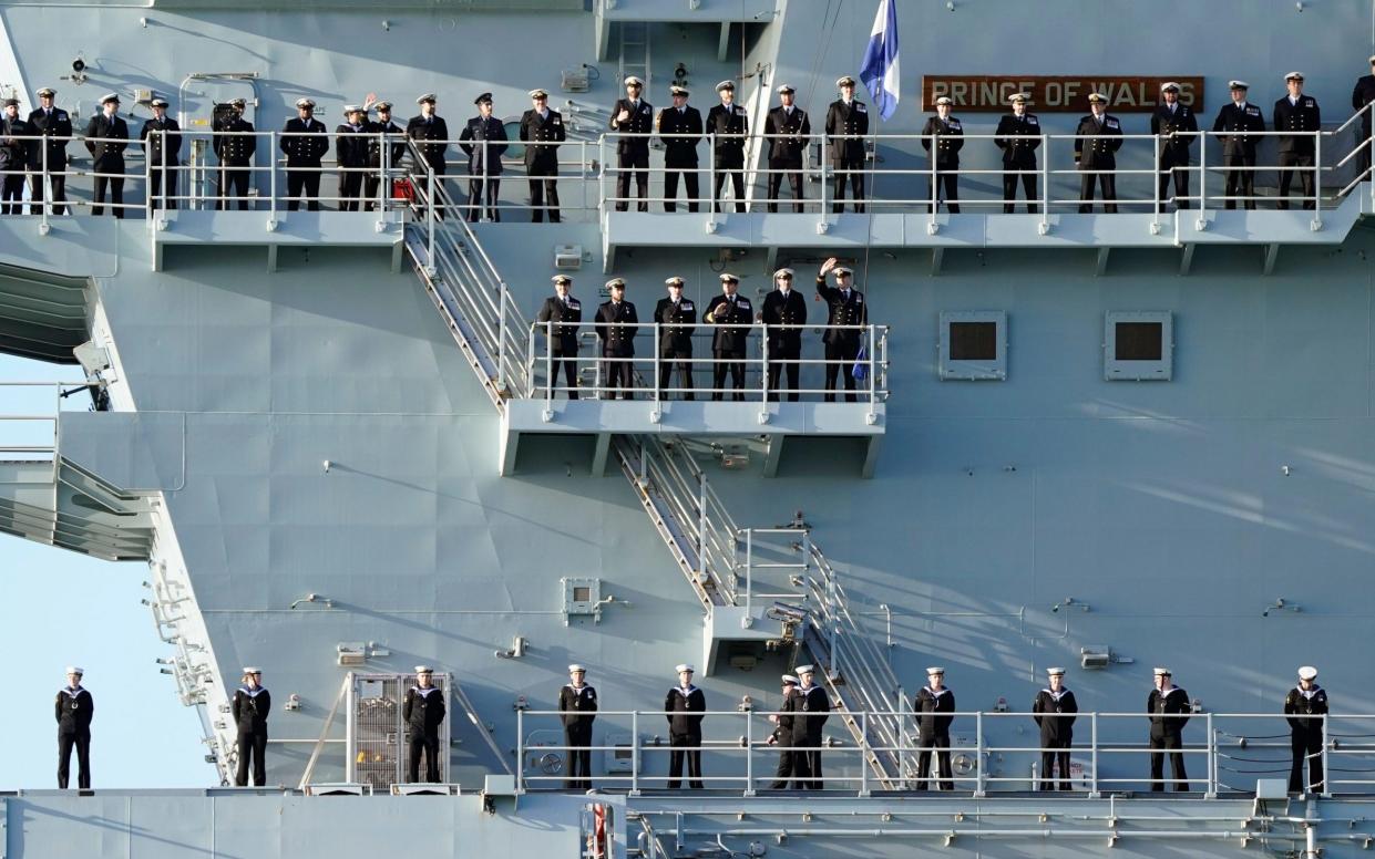 Sailors line up on the side of the Royal Navy aircraft carrier HMS Prince of Wales as it returns to Portsmouth Naval Base following a three-month deployment to the Eastern Seaboard of the United States