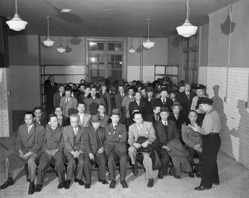 Two immigration officers interrogate Chinese immigrants suspected of being Communists or deserting seamen at Ellis Island. | Bettmann Archive/Getty Images