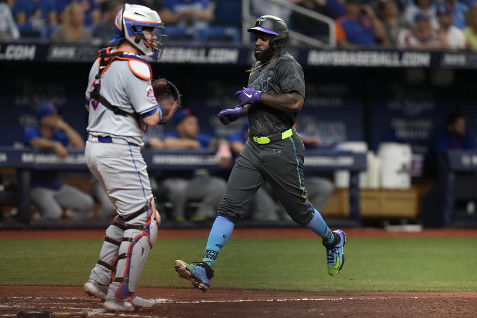 Tampa Bay Rays' Randy Arozarena, right, scores in front of New York Mets catcher Tomas Nido on a sacrifice fly by Alex Jackson during the third inning of a baseball game Friday, May 3, 2024, in St. Petersburg, Fla. (AP Photo/Chris O'Meara)