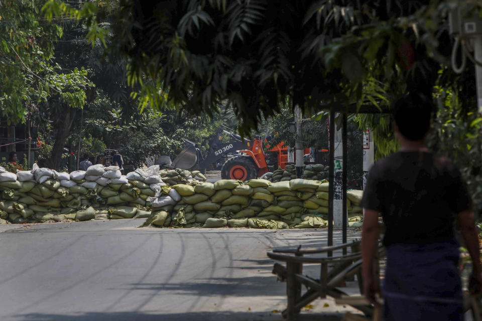 A man watches as soldiers use a bulldozer to remove sandbag barricades put in place by anti-coup protesters to protect them from security forces in Mandalay, Myanmar, Thursday, March 18, 2021. (AP Photo)