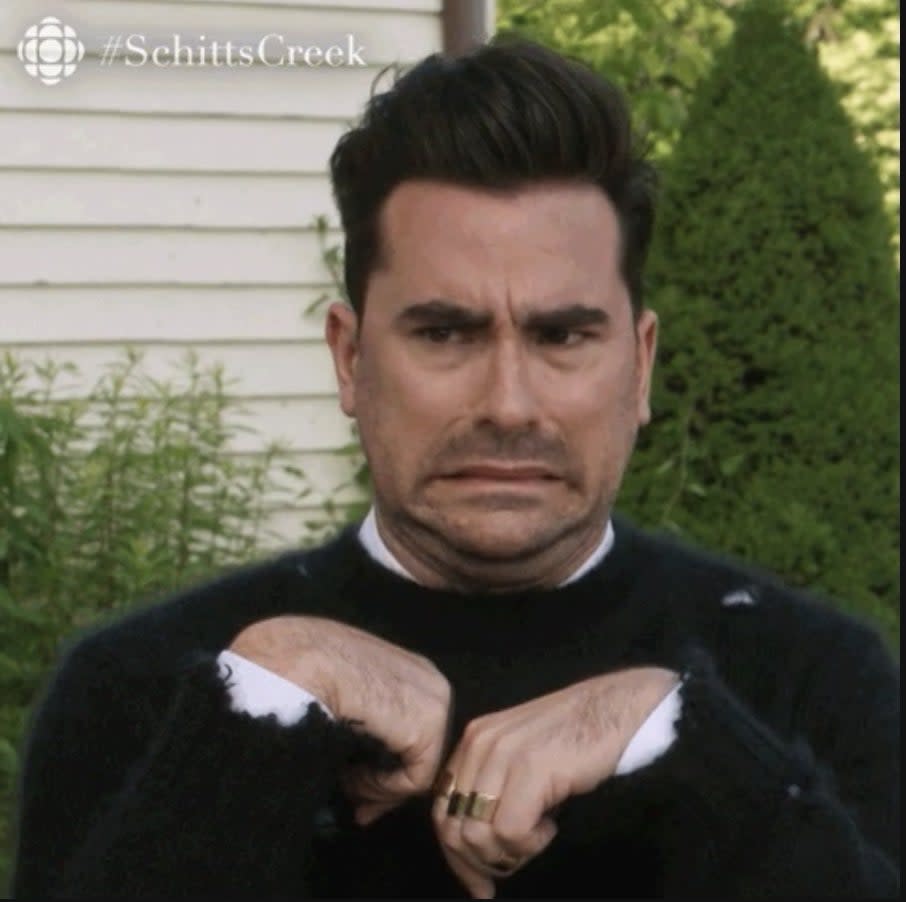 Dan Levy has a humorous, uncomfortable expression with hands pulled to his chest in a scene from Schitt's Creek