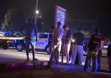 Bystanders watch over the scene at a movie theatre where a man opened fire on film goers in Lafayette, Louisiana July 23, 2015. REUTERS/Lee Celano