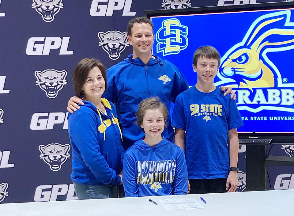 Great Plains Lutheran senior long-distance running standout Halle Bauer (front) signed to compete in track and field and cross country for South Dakota State University on Wednesday. She is pictured where her parents Sarah and Matt and her younger brother Jarret.