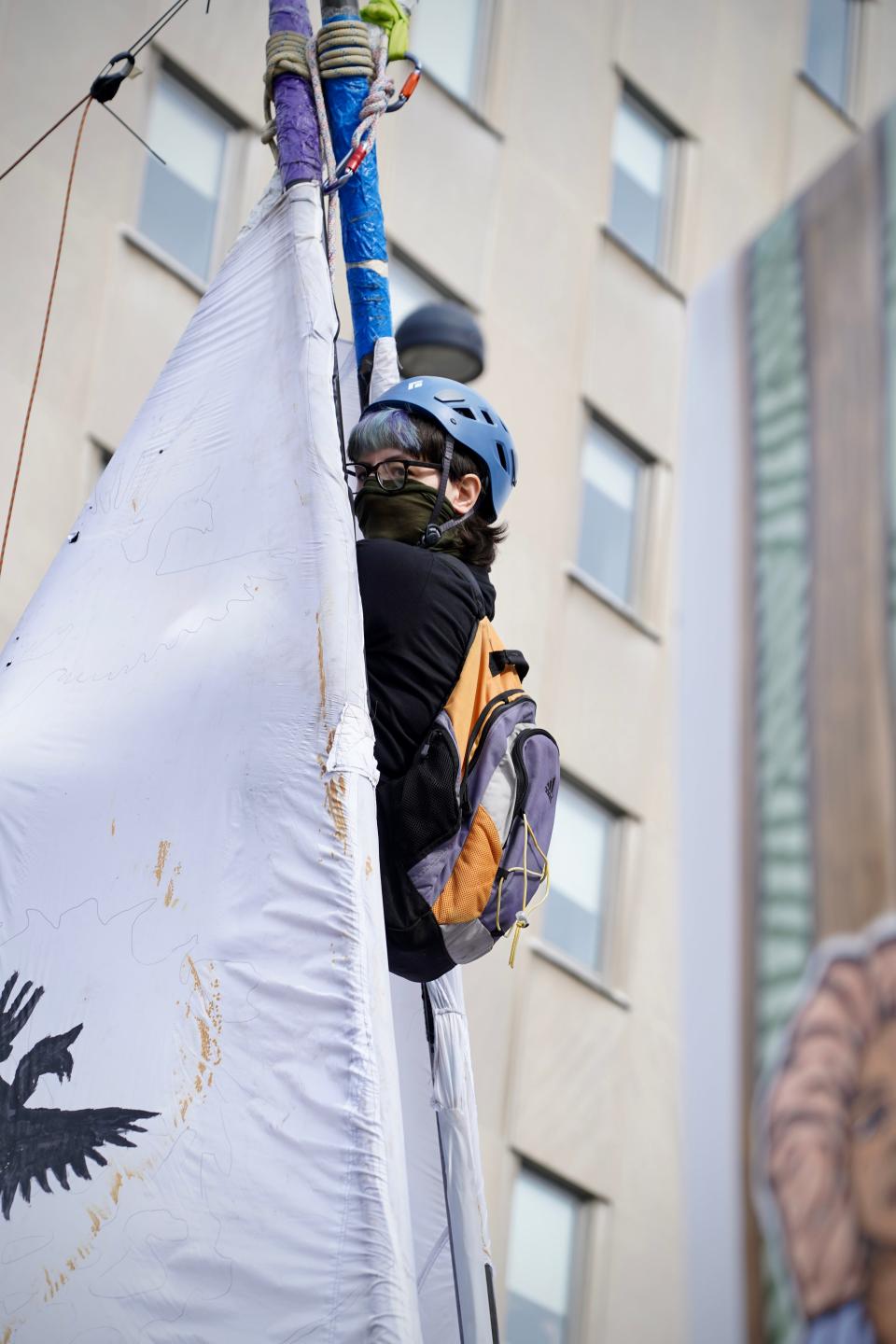Nony Rose Salyer, 31, hanging from a tripod during an environmental protest outside P&G's headquarters on Tuesday, June 7, 2022.