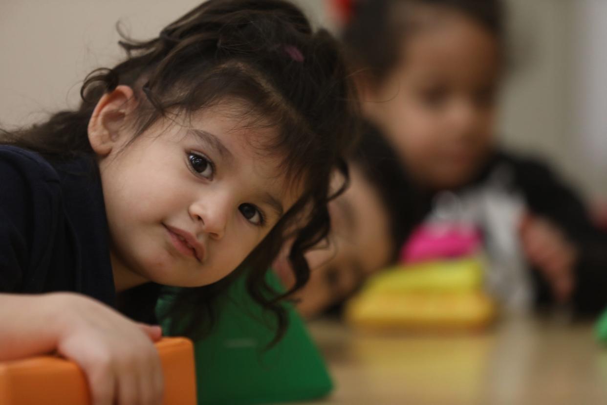 Dayaxielis Ramos and Lyan Maldonado try to catch the photographer's attention while Ashley Martinez works on shapes in her preschool class at School 9.
