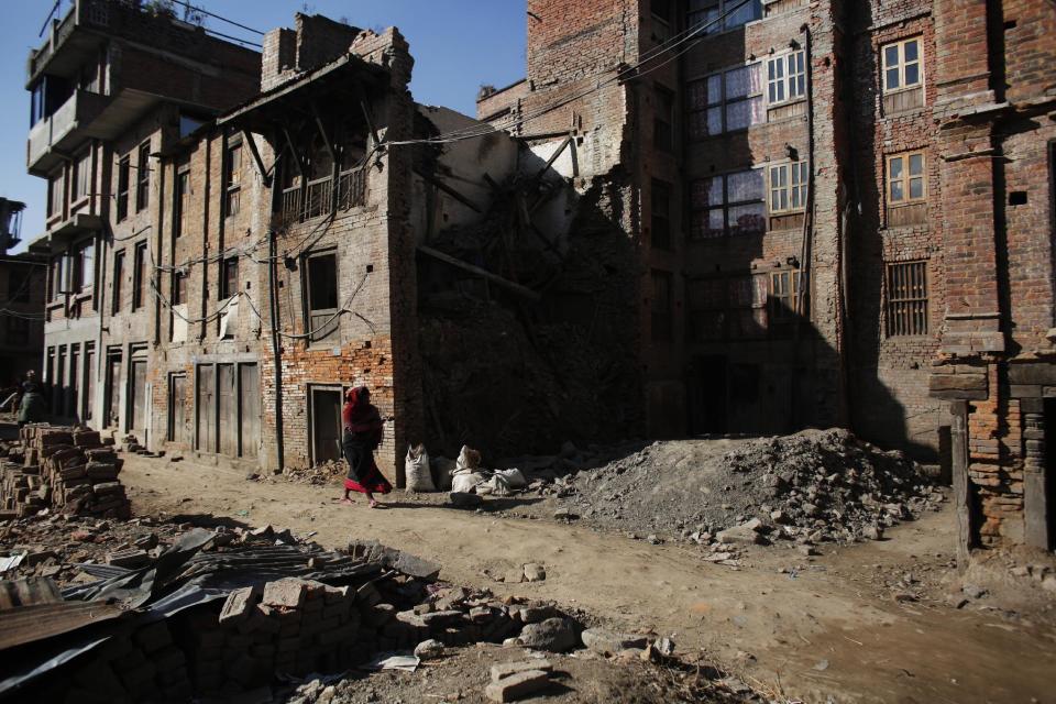 A Nepalese woman walks past houses that were damaged in the 2015 earthquake in Bhaktapur, Nepal, Wednesday, Jan. 4, 2017. Hundreds of houses were damaged during the April 25, 2015, earthquake in the town of Bhaktapur, which is known for brick paved roads, old palaces and artistic Hindu temples. The National Reconstruction Authority has said it has distributed the first installment of government grant money, about $500 to 450,000 families, but it is still collecting details from residents in several districts where the earthquake caused damage. (AP Photo/Niranjan Shrestha)