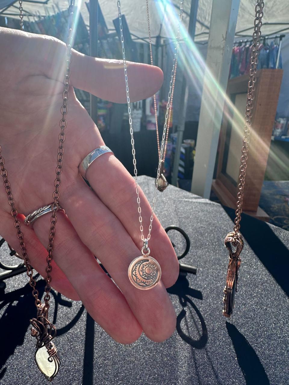 An image of a hand holding a shiny silver necklace.