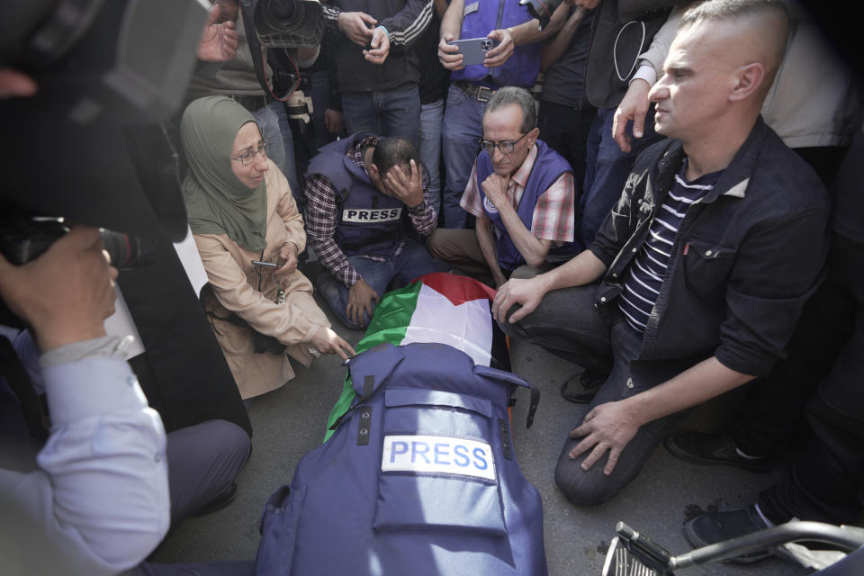 FILE - Journalists surround the body of Shireen Abu Akleh, a colleague with Al Jazeera, in the West Bank town of Jenin, Wednesday, May 11, 2022. The well-known Palestinian reporter for the broadcaster's Arabic language channel was shot and killed while covering an Israeli raid in the occupied West Bank town of Jenin early Wednesday, the Palestinian health ministry said. (AP Photo/Majdi Mohammed, File)