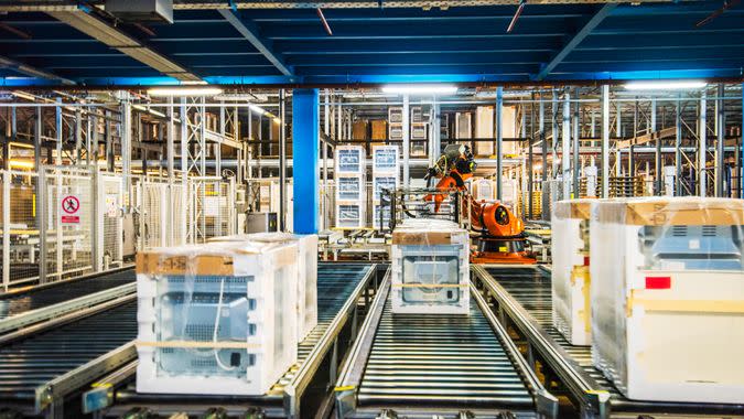 Household appliance assembly line with a conveyor belt and automated robotic arms.