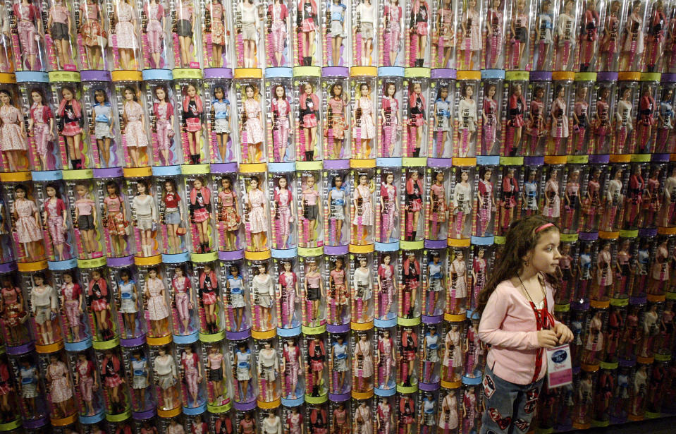 FILE - In this Thursday, Feb. 17, 2005 file photo, Ashley Cebollero, of New York, looks around in front of a bank of Barbie Fashion Fever dolls in New York. Debuting in 1959, Mattel’s 11.5-inch blond fashion doll has long held the No. 1 doll title with an estimated $1.3 billion in annual sales. (AP Photo/Gregory Bull, fIle)