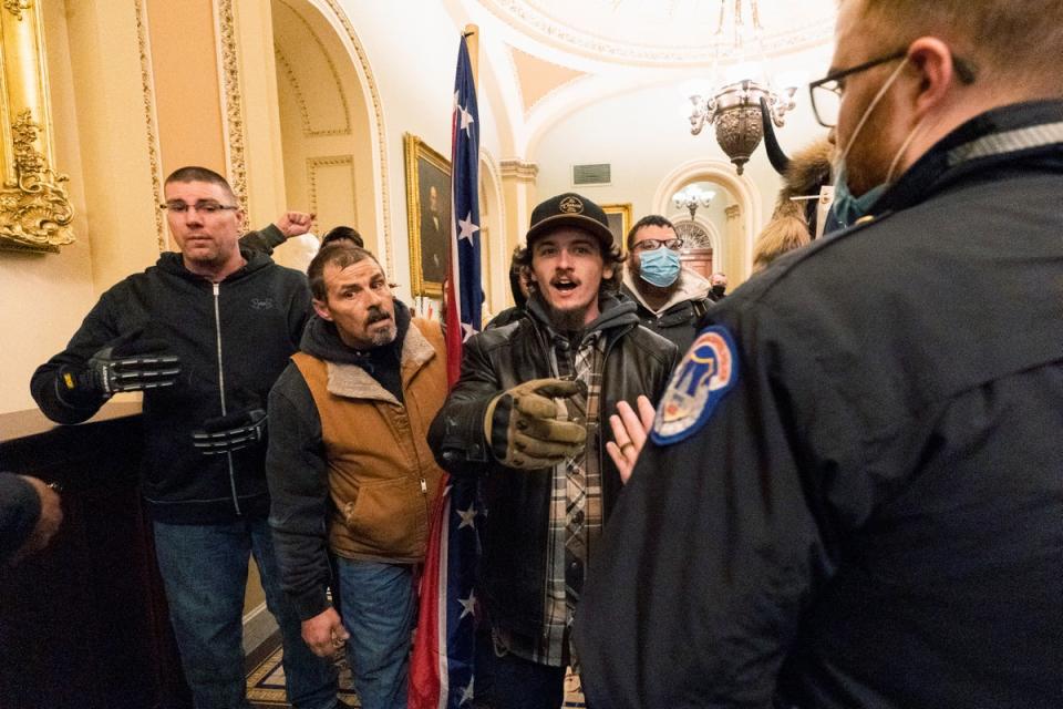 Kevin Seefried, second from left, holds a Confederate battle flag during a riot at the US Capitol on 6 January, 2021. (AP)