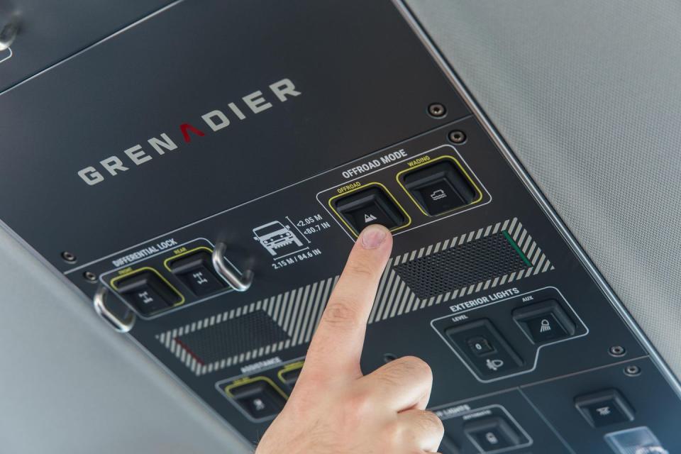 a hand pushing button on overhead console of 2025 ineos grenadier quartermaster pickup