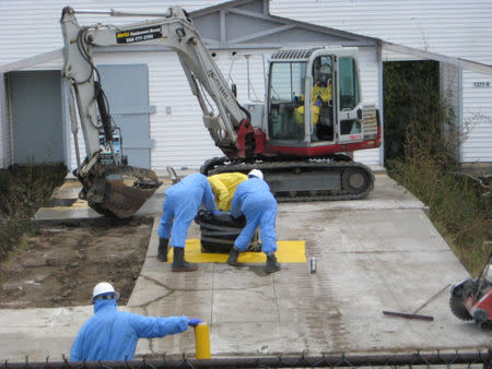 Workers remove a radioactive hotspot under the carport of an unoccupied home on Westside Drive on Treasure Island, near San Francisco, California U.S. in this June 2009 handout photo. Handout via REUTERS