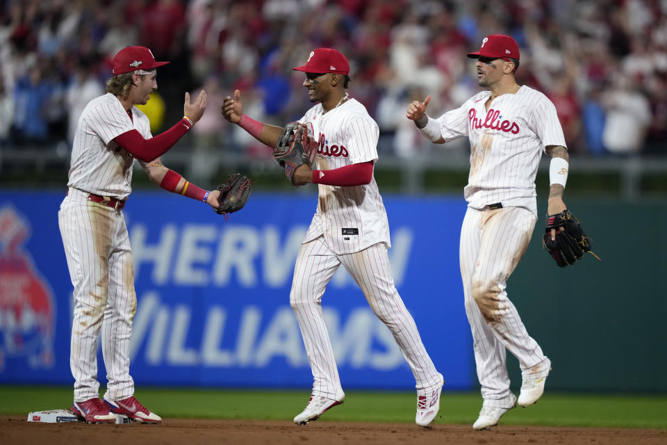 De izquierda a derecha, Bryson Stott, el dominicano Johan Rojas y Nick Castellanos festejan la victoria de los Filis de Filadelfia sobre los Marlins de Miami, en el primer juego de la serie de comodín de la Liga Nacional, el martes 3 de octubre de 2023 (AP Foto/Matt Slocum)