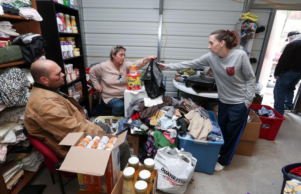 Tina Miller, right, accepted a bag from Donna Roark on Dec. 12, 2022, so she could gather items for herself and Brandon Hall, left, at The People's Building in Littcarr, Ky. Miller said, "FEMA is a joke."